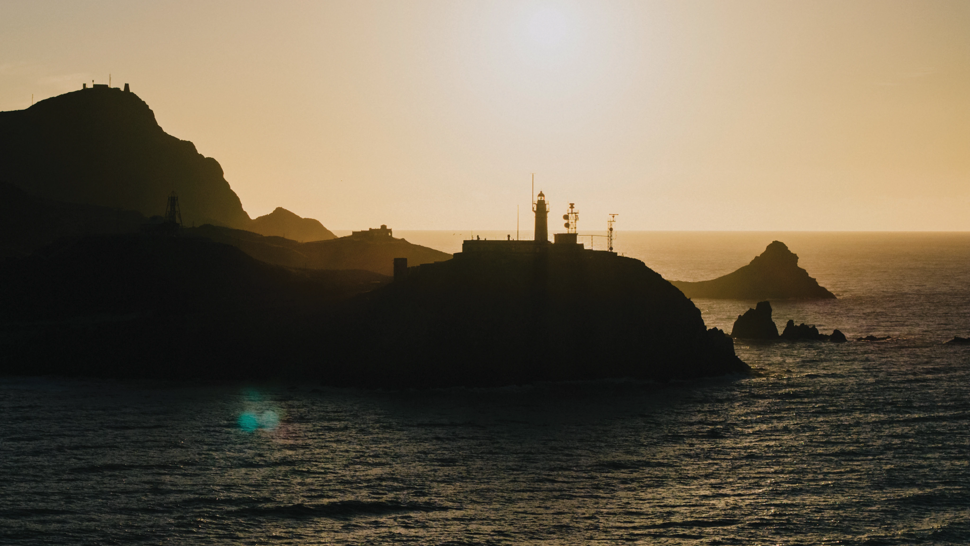 Stage 100 — coastal lighthouse at sunset, aerial view